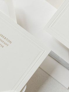 two white wedding cards with gold lettering on the front and back, sitting next to each other