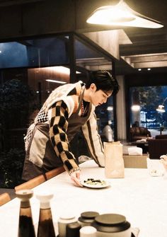 a woman standing over a plate of food on top of a table in a restaurant