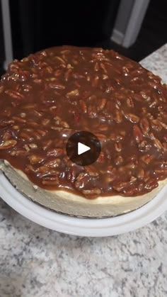 a cake covered in caramel and nuts on a white plate sitting on a counter