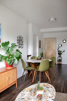 a dining room table with green chairs and a potted plant on top of it