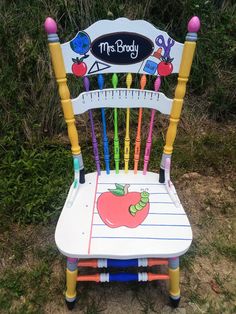 a wooden chair with an apple on the back and ruler painted on it's seat