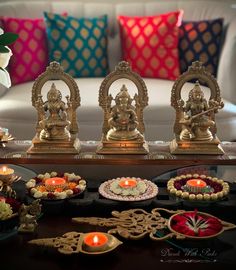 a table topped with lots of different types of decorations and candles in front of a couch