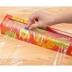 a person is cutting up some fruit in a plastic bag on a wooden surface with scissors