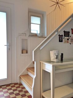 a staircase leading up to a small room with a checkered floor and white walls