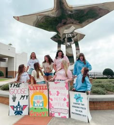 a group of women standing next to each other in front of a statue with a plane on it