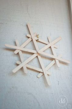 a snowflake made out of popsicle sticks sitting on top of a white wall