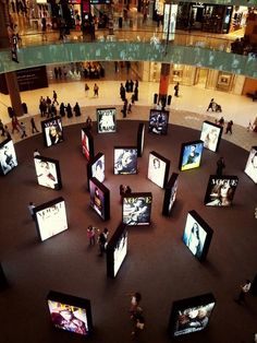 an overhead view of people walking around televisions in a shopping mall with multiple screens on the floor