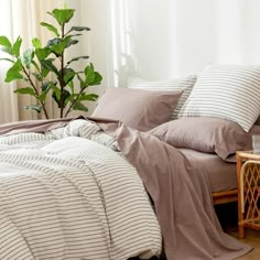 a bed with two pillows on top of it next to a table and potted plant