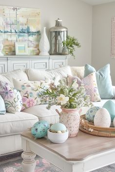 a living room filled with white furniture and lots of colorful eggs on the coffee table