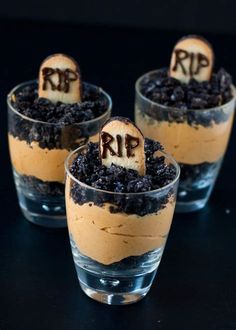 three desserts in small glasses with dirt on the bottom and letters carved into them