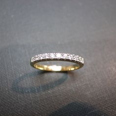 a yellow gold wedding band with white diamonds on the inside and outside, sitting on a black surface