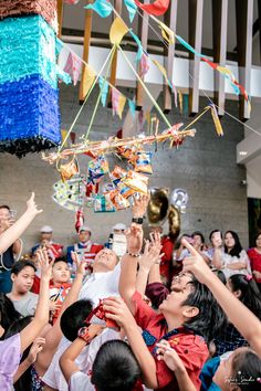 a group of people standing around each other with their hands in the air and decorations hanging from them