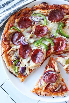 a pizza with pepperoni, onions and green peppers on a white serving platter