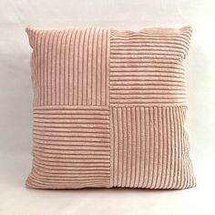 a pink pillow with pleated fabric on the front and back, sitting on a white surface