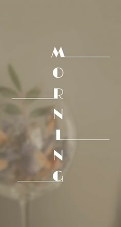 the word morning is written on top of a glass vase filled with flowers and leaves