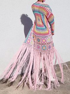 a woman standing on the sidewalk wearing a dress with fringes and crochet