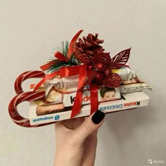 a person holding up a box filled with chocolates and candy bar wrapped in red ribbon