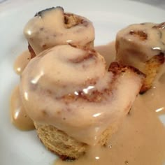 two cinnamon rolls covered in icing on a white plate with caramel glaze