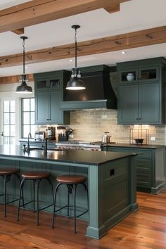 a large kitchen with wooden floors and green cabinetry on the walls, along with bar stools