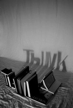 three books sitting on top of a bed next to a wall