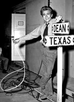 a black and white photo of a man standing next to a sign that says dean texas