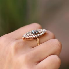 a woman's hand holding a gold ring with blue and white stones on it