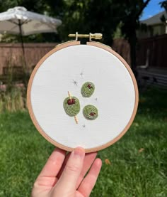 someone is holding up a small embroidery project