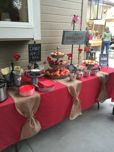 a red table topped with lots of food and desserts on top of it's sides