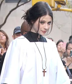 a woman in a priest's outfit walking down the street with people behind her