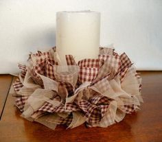 a white candle sitting on top of a table next to a brown and white cloth