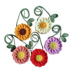 four crocheted flowers with green stems and leaves on them, all in different colors