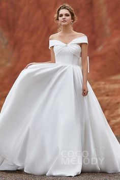 a woman in a white wedding dress standing on the ground with her hand on her hip