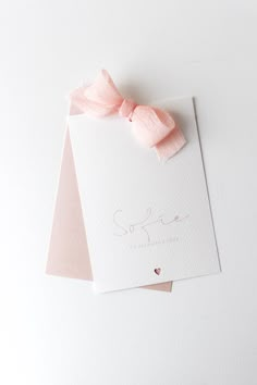 two cards with pink bows on them sitting next to each other