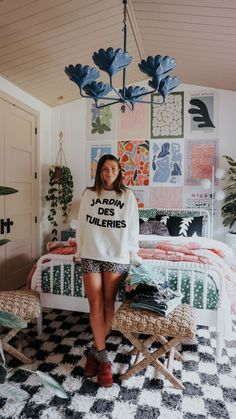 a woman standing in front of a bed wearing a japan tuileries sweatshirt and shorts