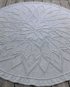 a white rug on top of a wooden floor with an intricate design in the middle