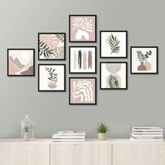 a set of nine framed art prints hanging on a wall above a white dresser with books and plants