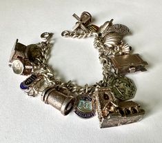 a sterling charm bracelet with an assortment of charms, some mechanical.  the chain was not marked but tests as sterling, some of the charms are marked as sterling or silver, but many are not.  i suspect that most of them are silver, not so sure about the book shape that says London.  the mechanical ones include a church that opens with a  couple being wed, a windmill, a clamshell with pearl inside, a beer stein, and what i believe is a rest room with revolving man/woman.  this looks like it was someone's travel collection, perhaps from a honey moon trip.  it has some nice weight. length of chain:  7" weight:  59.3g Luxury Heirloom Style Bracelets With Vintage Charm, Sterling Silver Charms Bracelet Collectible, Luxury Heirloom Bracelet With Vintage Charm, Antique Silver Charm Bracelet, Silver Engraved Charm Bracelet, Sterling Silver Bracelet With Vintage Charm, Sterling Silver Bracelet With Charms For Collectors, Silver Sterling Vintage Charm Bracelet, Antique Silver Metal Charm Bracelet