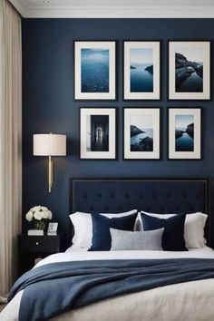 a bedroom with dark blue walls and pictures on the wall above the bed, along with white pillows