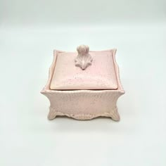 a small pink box with a flower on the lid and a leaf decoration at the top