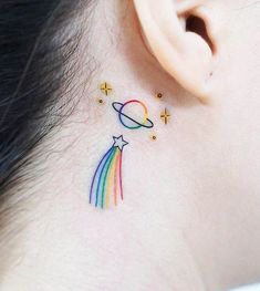 a woman's behind the ear tattoo with a rainbow and stars