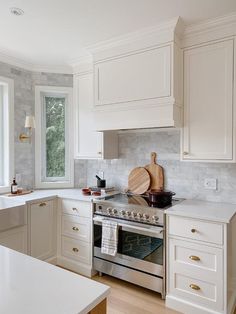 a kitchen with white cabinets and stainless steel stove top oven, dishwasher, and cutting board on the counter