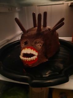 a chocolate cake decorated to look like a monster's head with teeth and tongue