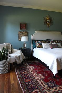 a bedroom with a bed, chair and rug