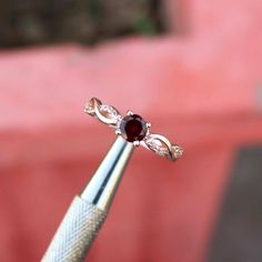 a close up of a diamond and garnet ring