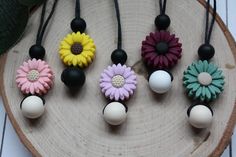 six flower necklaces are on a wooden board next to a green leafy plant