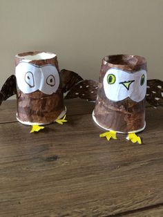 two owls made out of toilet paper sitting on a wooden table next to each other