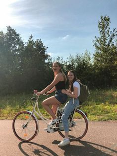 two women riding on the back of a bicycle