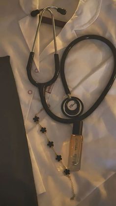 a black stethoscope laying on top of a white shirt and beaded necklace