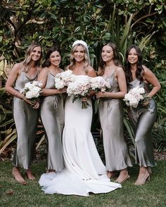 the bride and her bridesmaids pose for a photo in front of some greenery