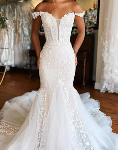 a woman wearing a white wedding dress standing in front of a mirror with her hands on her hips